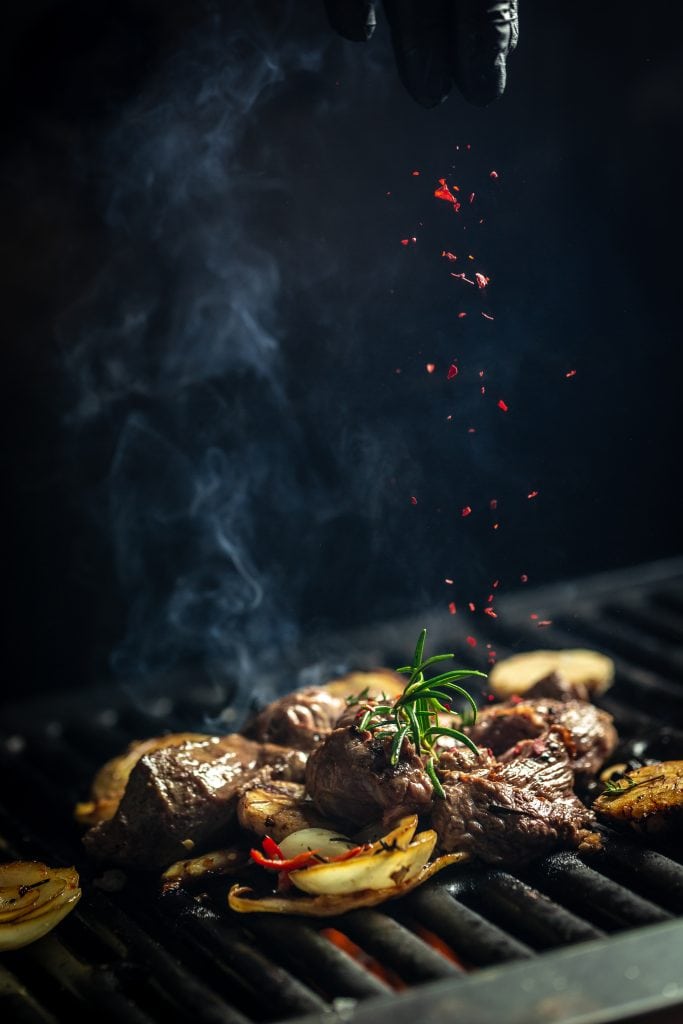 Smaakvolle biefstuk en groenten grillen op bbq, met verse kruiden en gekarameliseerde ui.